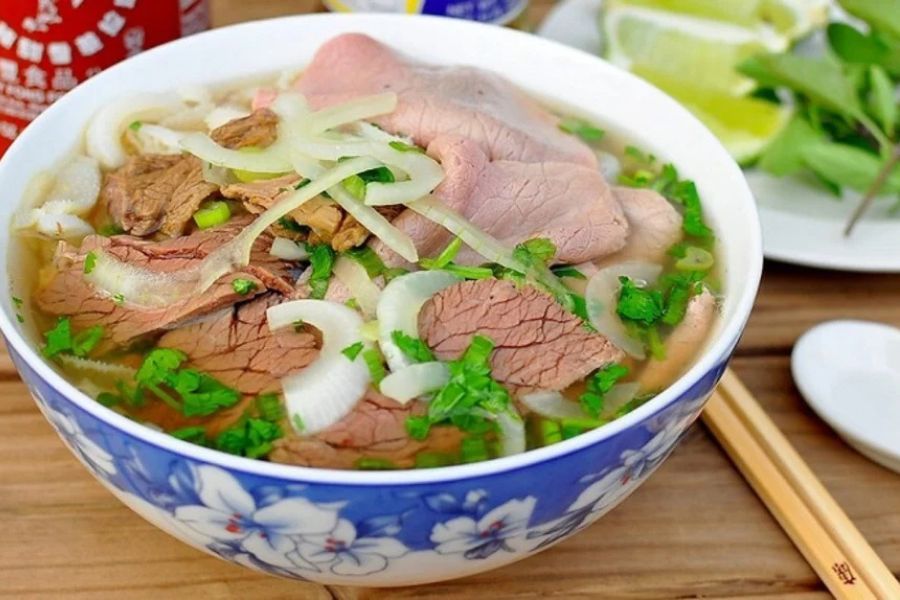 Bát phở bò nóng hổi tỏa khói trên bàn gỗ