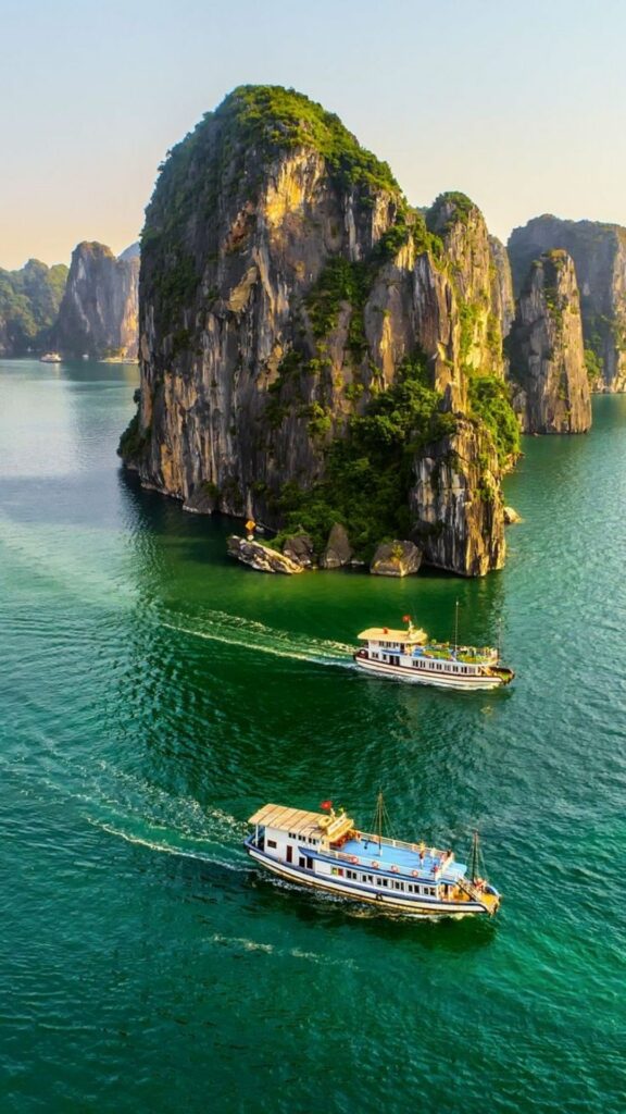 Du thuyền nhỏ giữa vịnh biển xanh và núi đá
