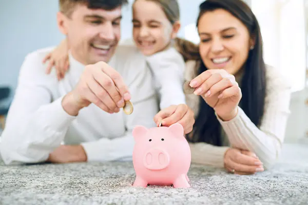 Gia đình ba người đang tiết kiệm bằng cách cho tiền vào heo đất