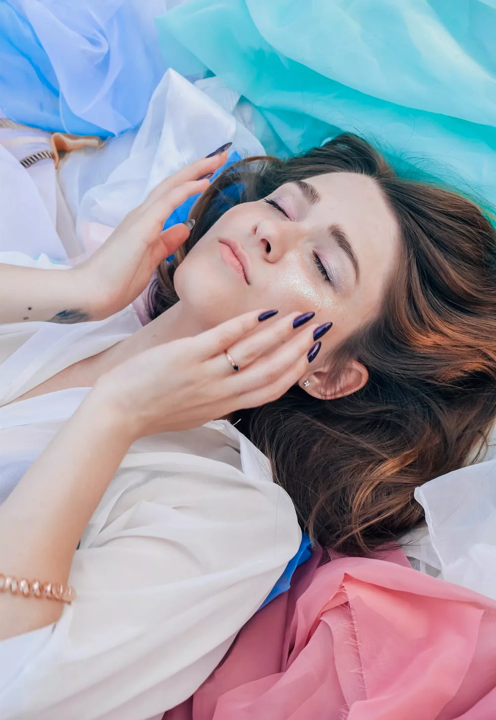 Cô gái nằm nhắm mắt đưa tay lên mặt-dưỡng da