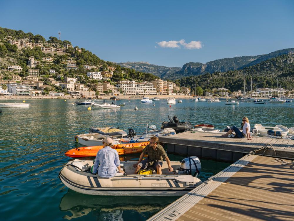 Thuyền neo đậu tại cảng Mallorca nắng vàng với những ngọn đồi phía sau