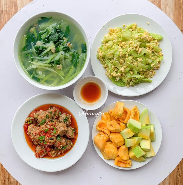 Bữa cơm đơn giản có canh bí, mướp đắng xào trứng, mọc sốt cà chua và các loại trái cây nhiệt đới
