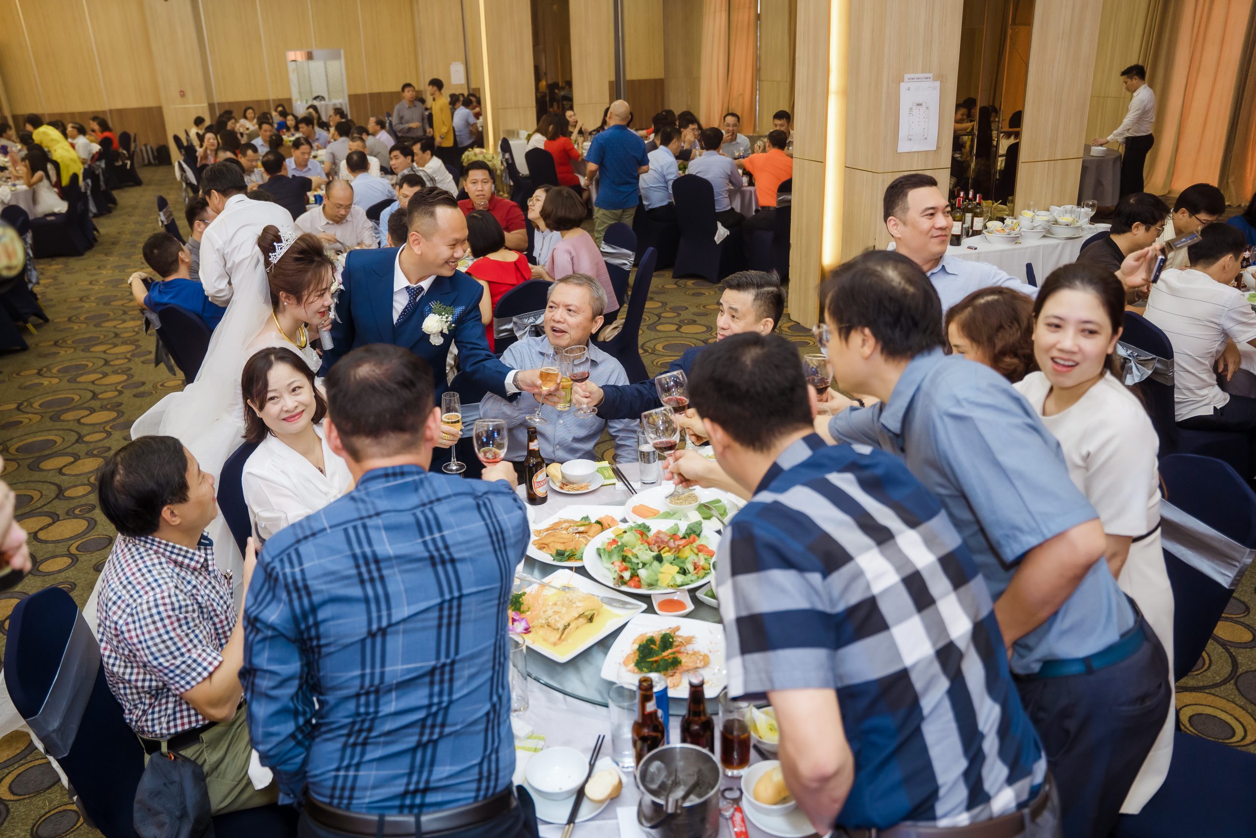 Không gian tiệc cưới với nhiều bàn tiệc được trang trí đẹp mắt và khách mời đang thưởng thức