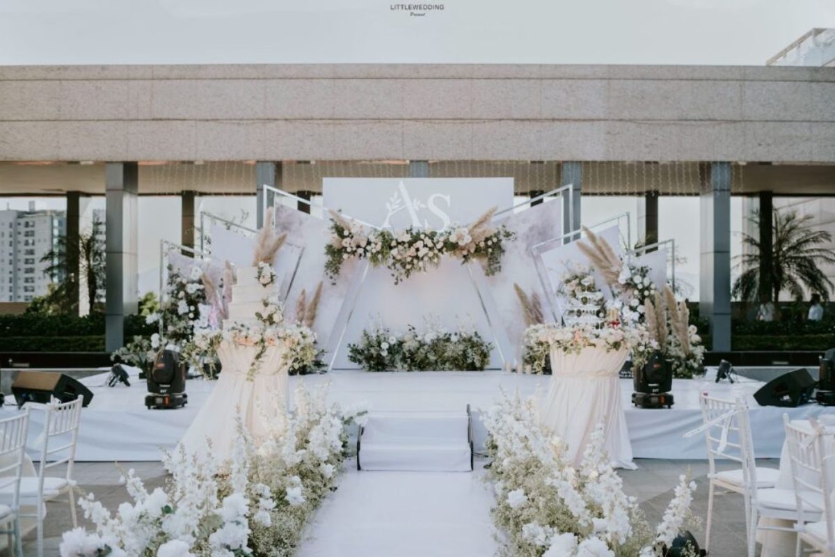 Sân khấu cưới tại nhà với background trắng và điểm nhấn hoa pastel nhẹ nhàng