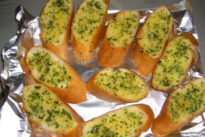 Phết đều hỗn hợp bơ lên từng lát bánh mì và xếp vào khay nướng