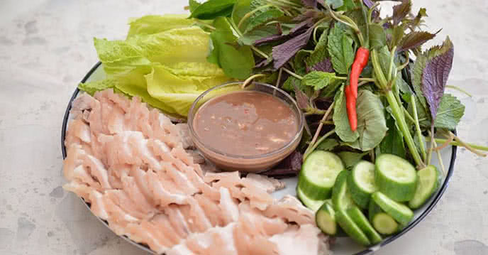 Mẹt nguyên liệu tươi sống với thịt ba chỉ, bún tươi và đa dạng các loại rau thơm chuẩn bị cho món cuốn
