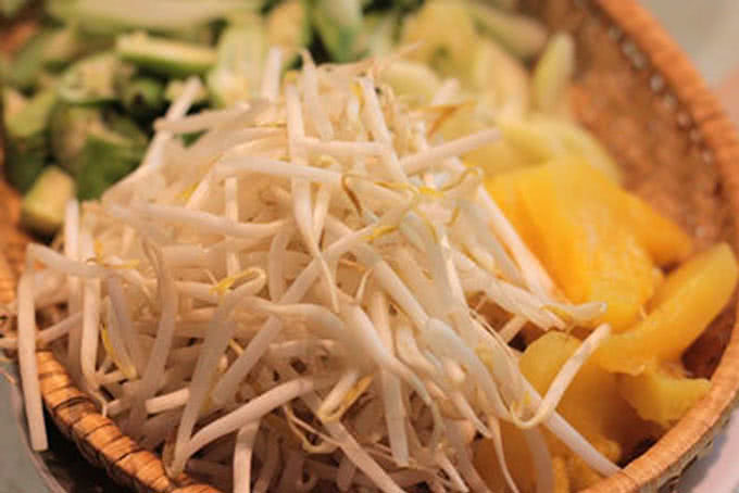Nồi nước dùng bún bò Huế đang sôi nhẹ với sả và gia vị