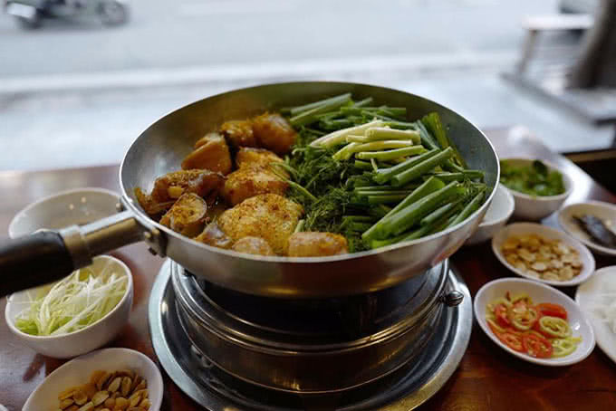 Nhân viên nhà hàng đang đảo cá trực tiếp trên chảo gang nóng hổi tại bàn cho thực khách
