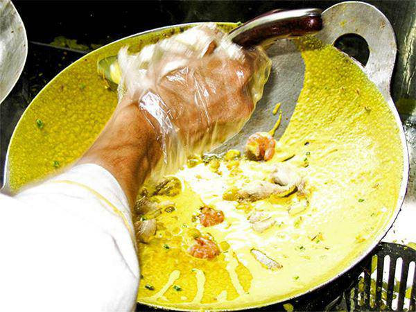Chiếc bánh xèo đang được rán trên chảo nóng, vỏ bánh vàng ươm và giòn rụm.
