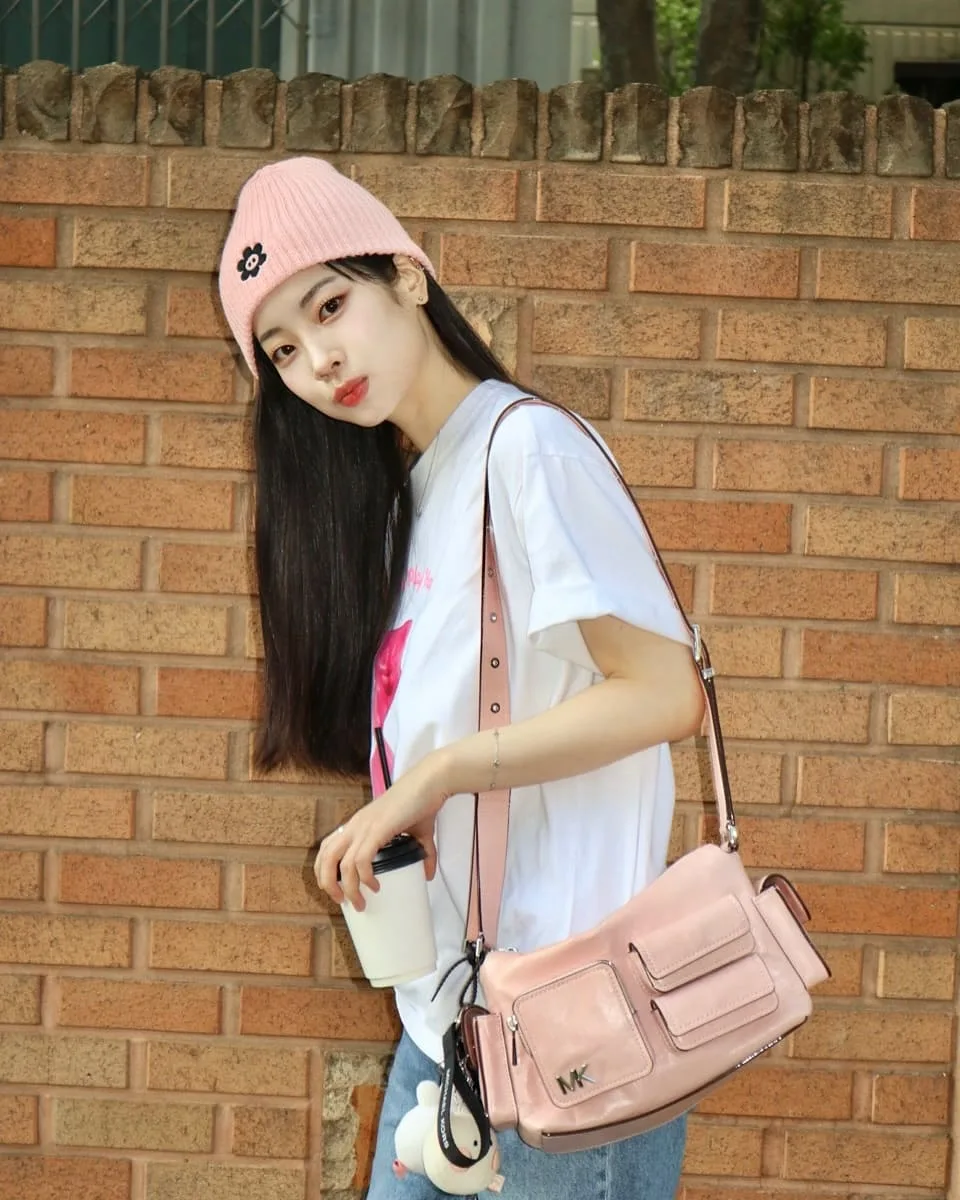 Túi xách màu hồng làm điểm nhấn nổi bật trên nền trang phục tối giản