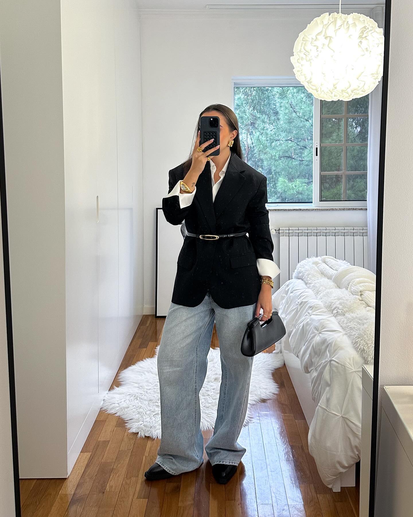 Áo khoác blazer đen phối cùng quần denim và túi xách da thanh lịch