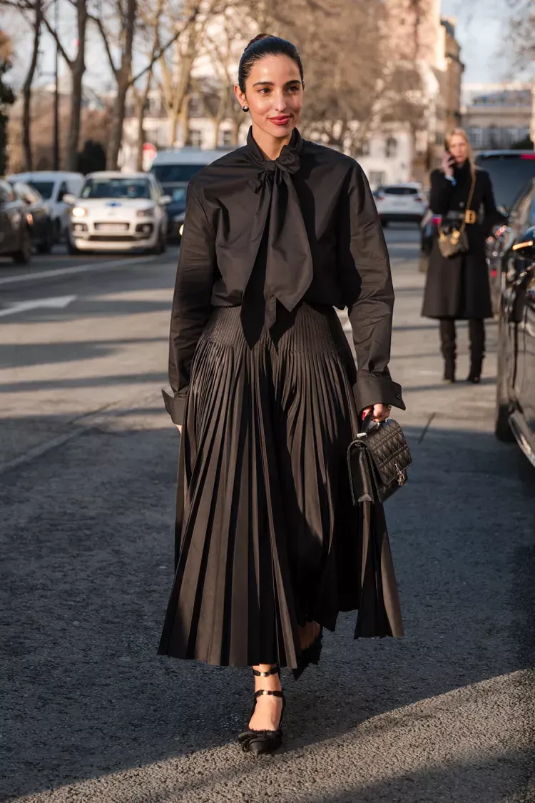 Set đồ all black với áo sơ mi lụa và chân váy xếp ly mang lại vẻ đẹp quyền lực