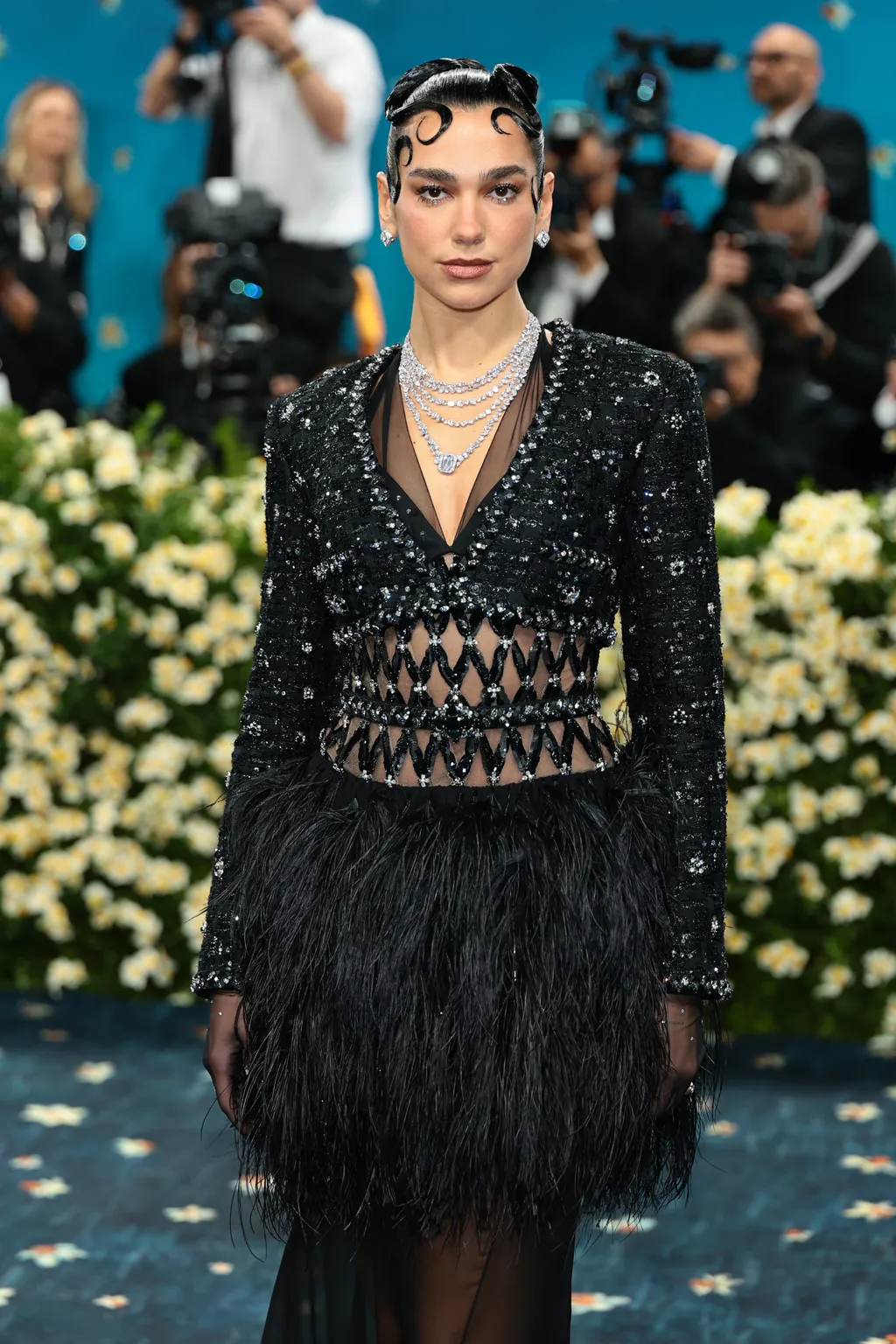 Dua Lipa với tóc được tạo kiểu xoăn tón và dây buộc tại Met Gala 2025