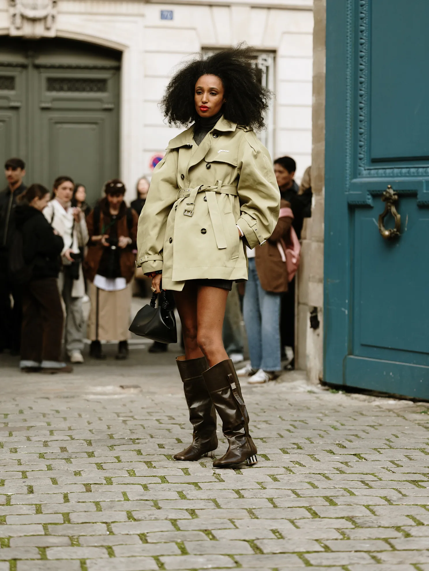 Outfit street style Paris mùa Thu 2025 với bốt nâu và chân váy mini xếp ly