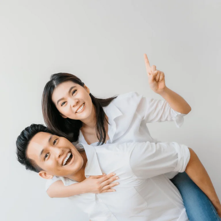 Đôi uyên ương mặc áo phông trắng cười đùa vui vẻ, chàng cõng nàng trên lưng giữa nắng vàng