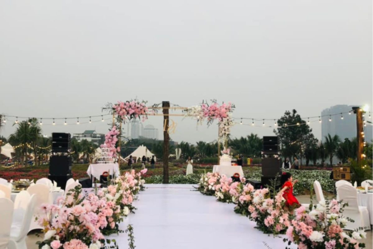 Concept trang trí tiệc cưới sử dụng khối màu hoa hồng nhạt và trắng tạo sự thanh thoát trên phông nền xanh mát của cảnh quan ngoài trời