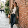 Người phụ nữ mặc trang phục casual đứng cạnh tường gạch đỏ trong ánh sáng dịu
