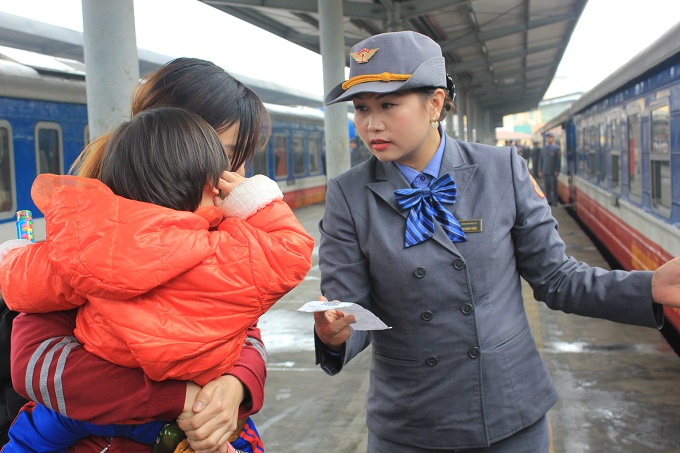 Nhân viên đường sắt hướng dẫn hành khách lên tàu