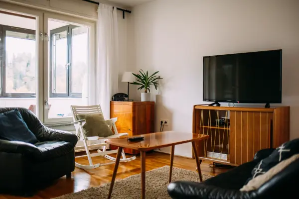 Phòng khách gọn gàng với ghế sofa, ghế bập bênh, bàn, tivi và cây cảnh.