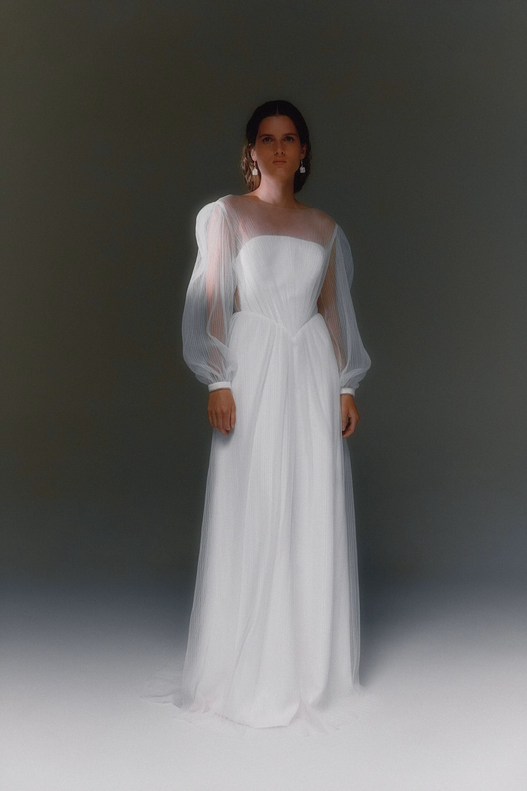 Váy cưới tulle gấp nếp với chi tiết lớp được sắp xếp thành các nếp gấp hình học, tạo chuyển động thanh lịch