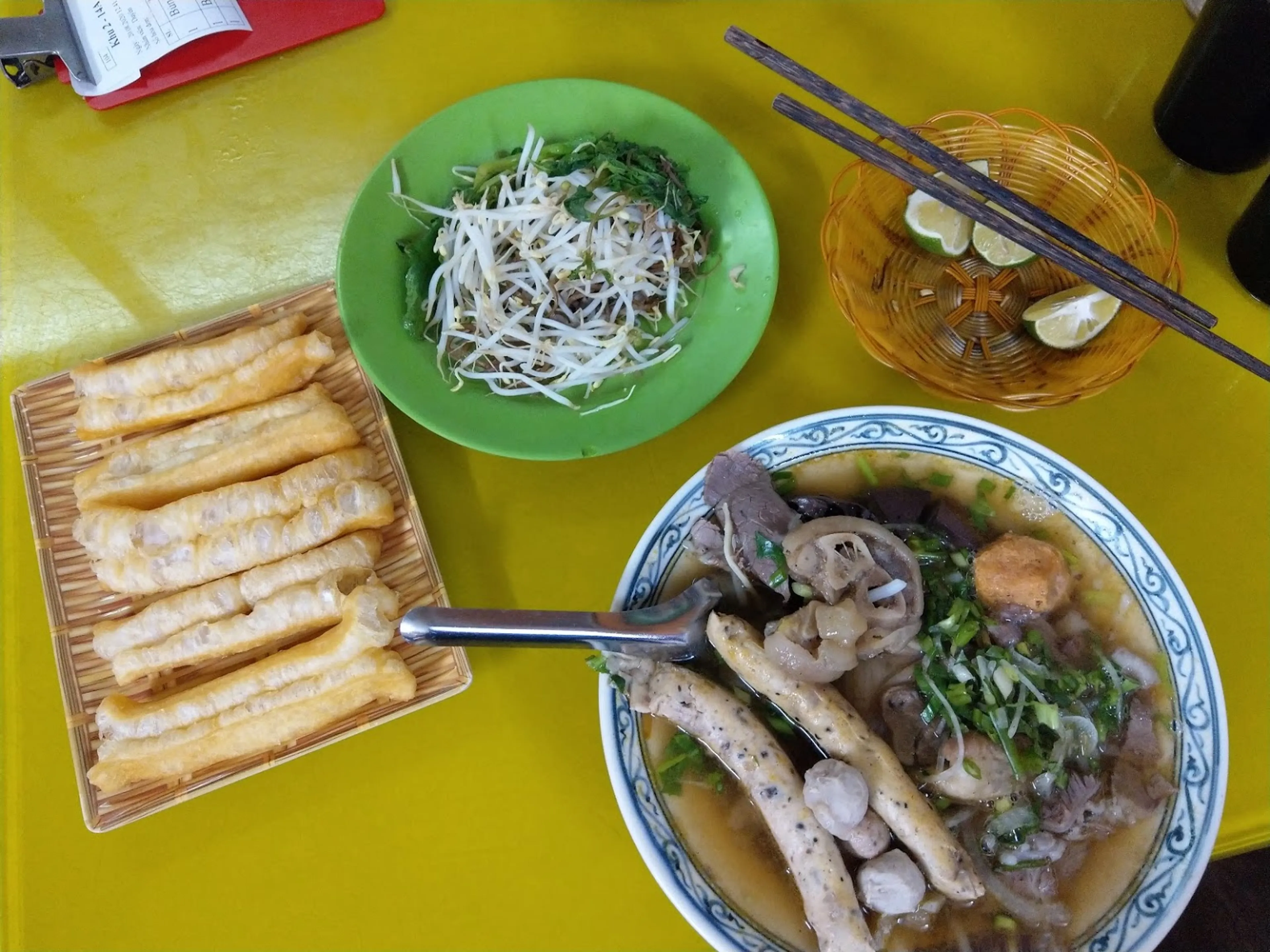 Bowls of bun bo Hue and cao lau side by side at a Hoi An market