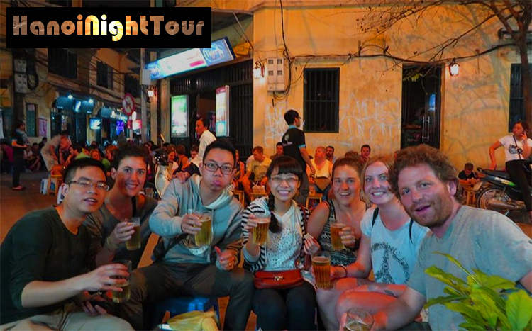A food tour group at a Hanoi night market sampling street food dishes